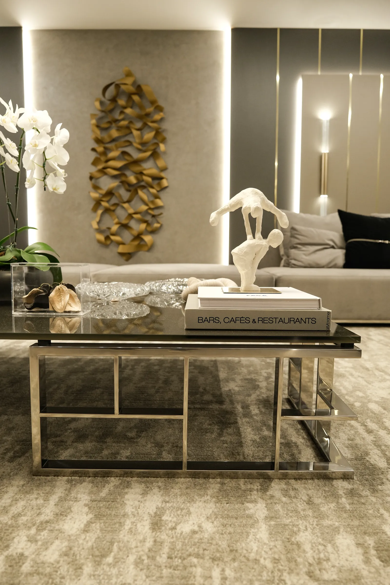 Sala de estar da Mostra Artefacto com painel dourado e escultura sobre mesa de centro