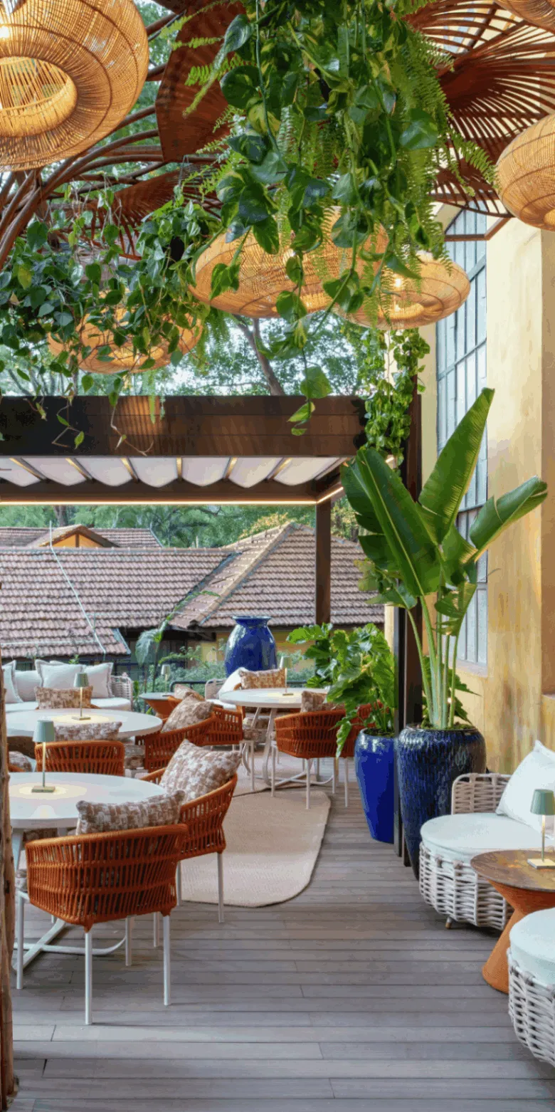 Terraço da Casa Buriti com plantas pendentes e poltronas de fibra
