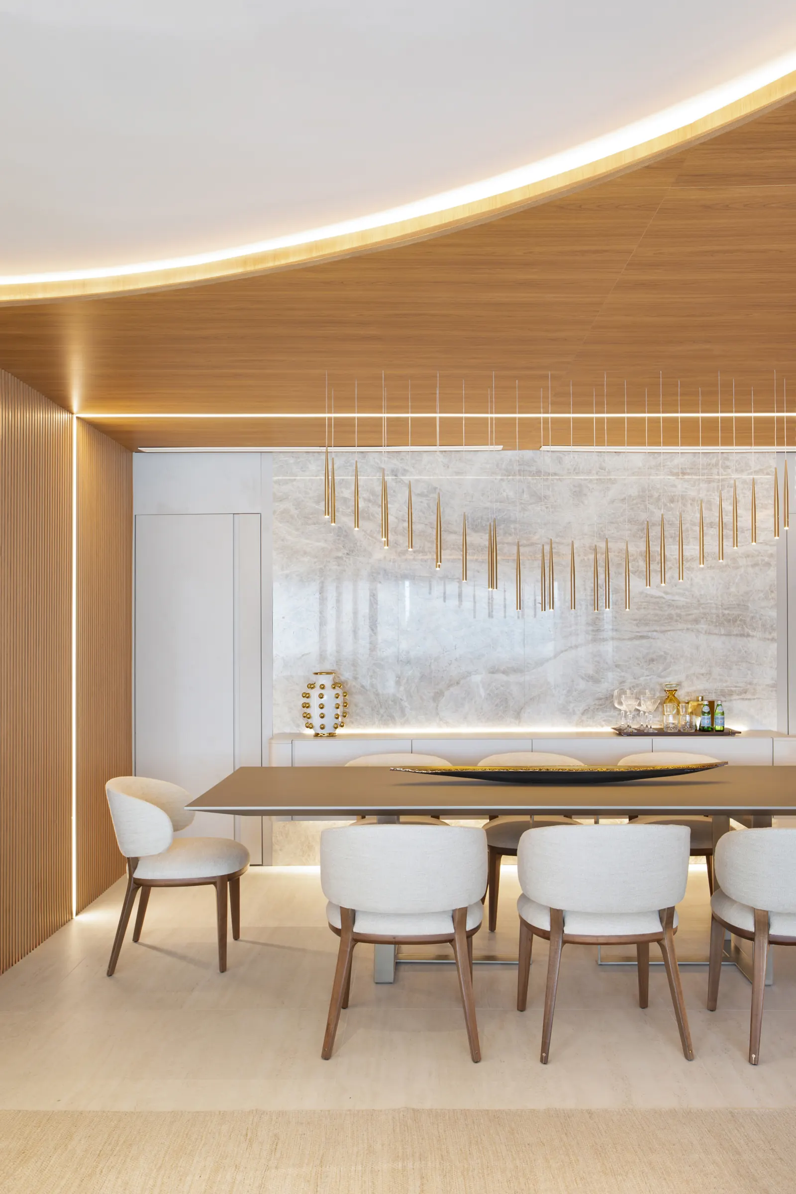 Sala de jantar com mármore travertino e pendentes dourados em cascata