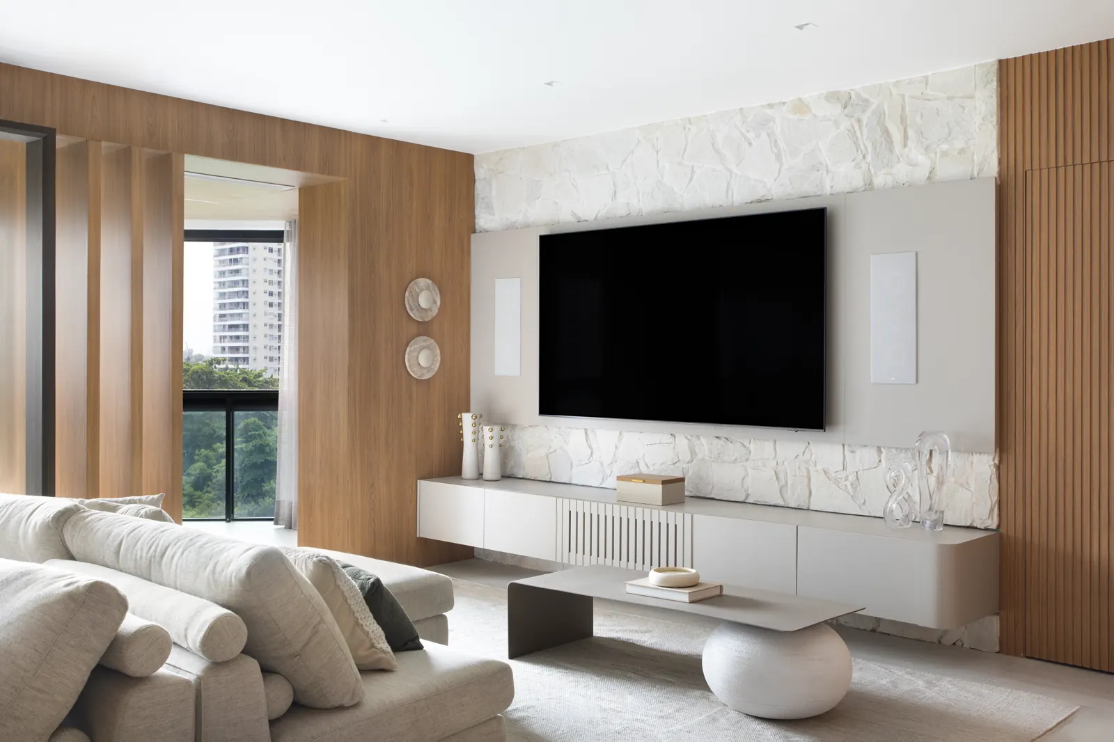 Sala de TV com parede em pedra natural rústica e marcenaria em madeira