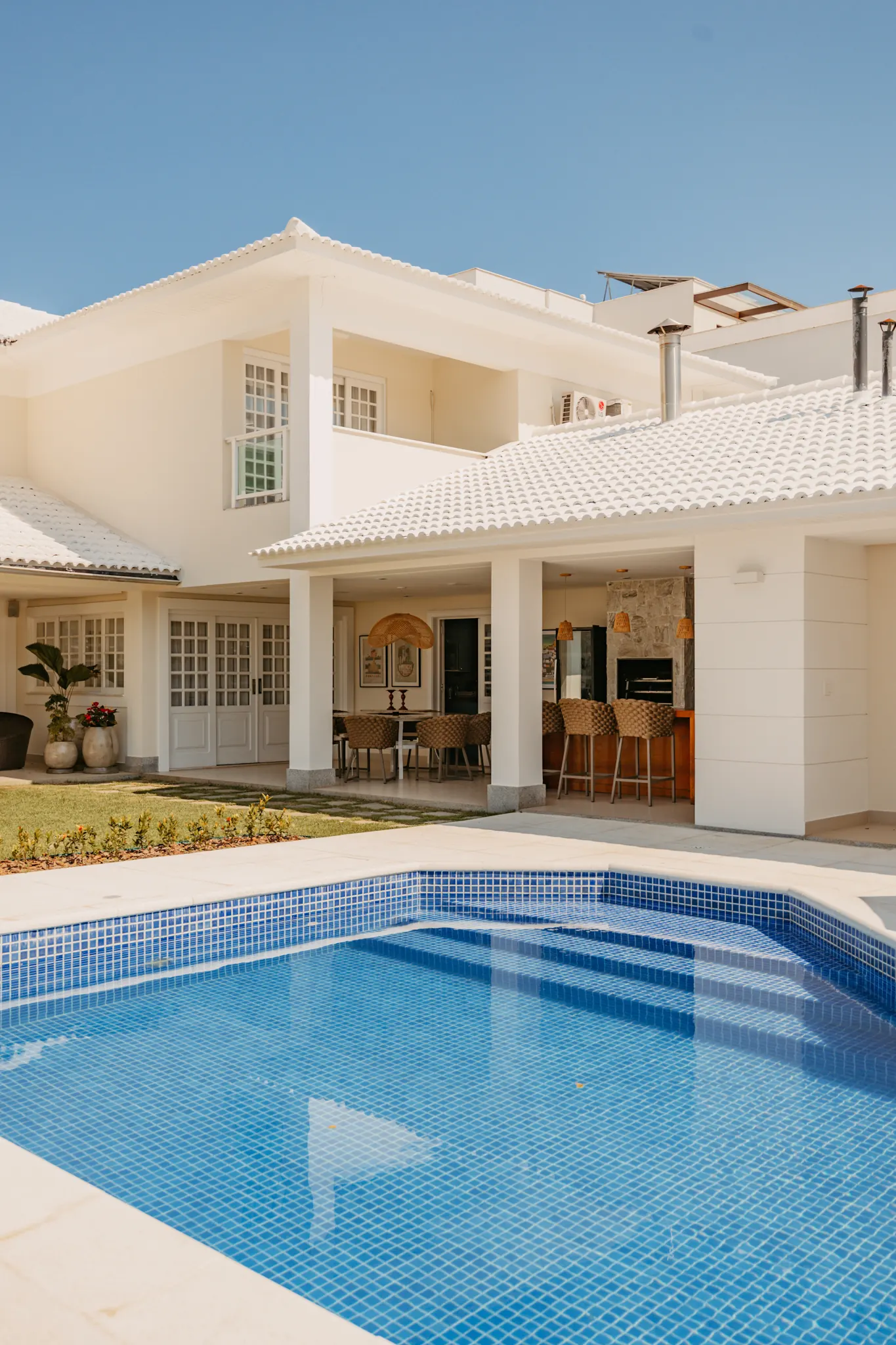 Residência de alto padrão com fachada clara, piscina e área social integrada
